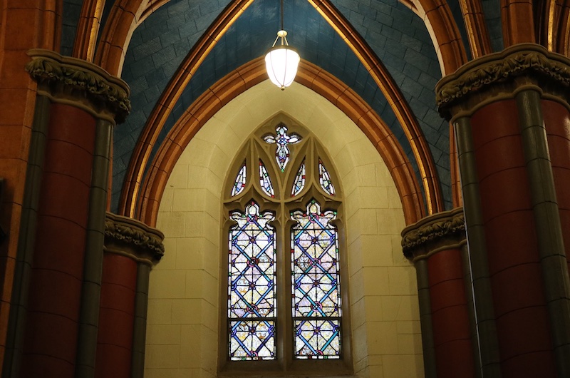 A stained glass window in the middle of dark blue arches.