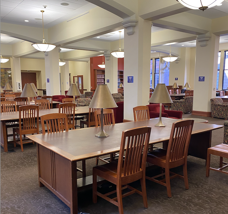 The inside of the Gottesman Libraries at Teachers College. There are brown wooden tables and chairs set up in rows.