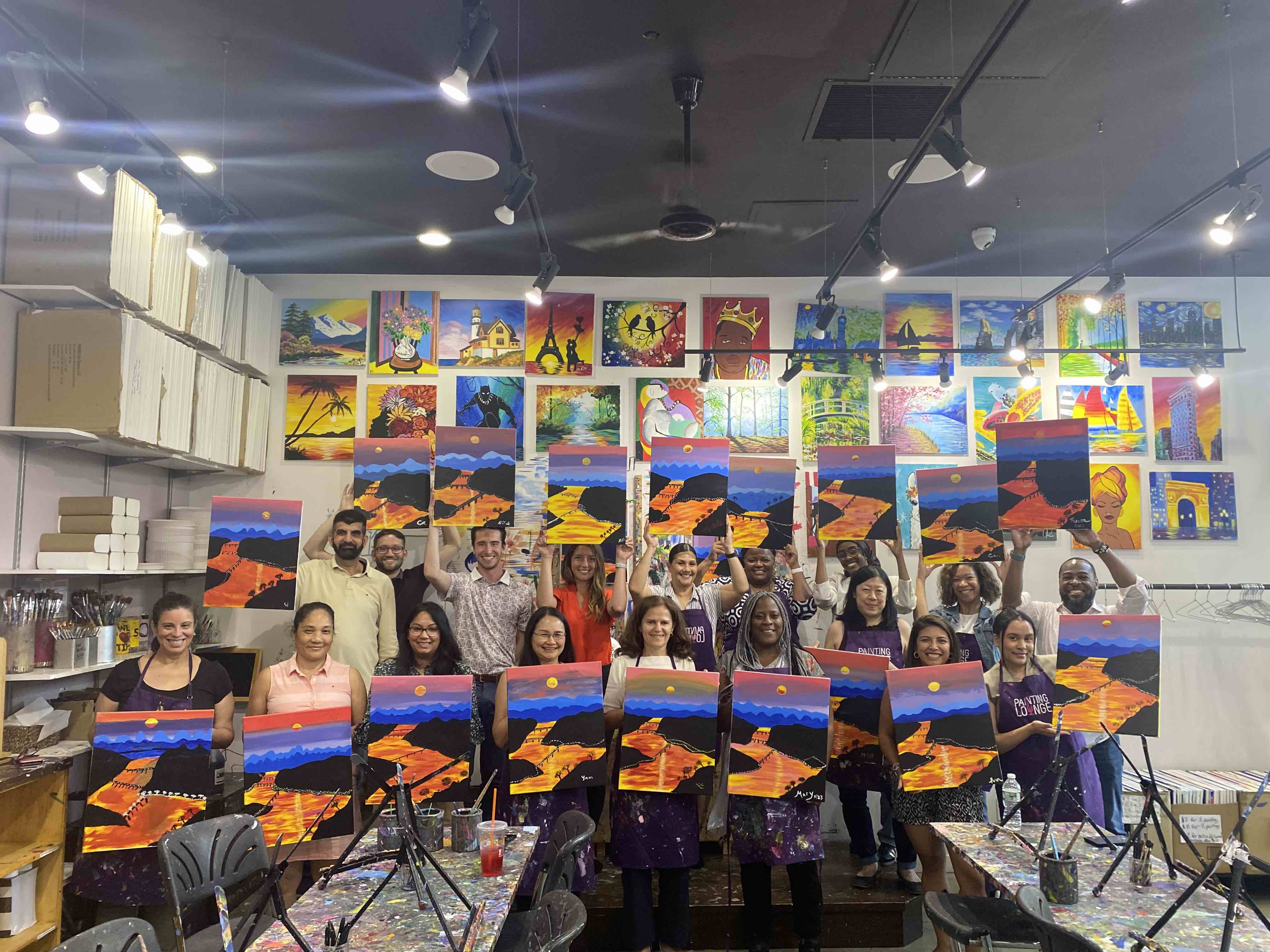 Image of people holding up paintings that they created in an art class