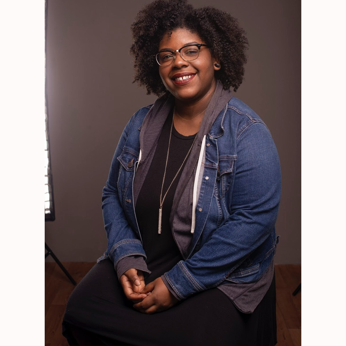 A person sitting on a chair against a gray background.