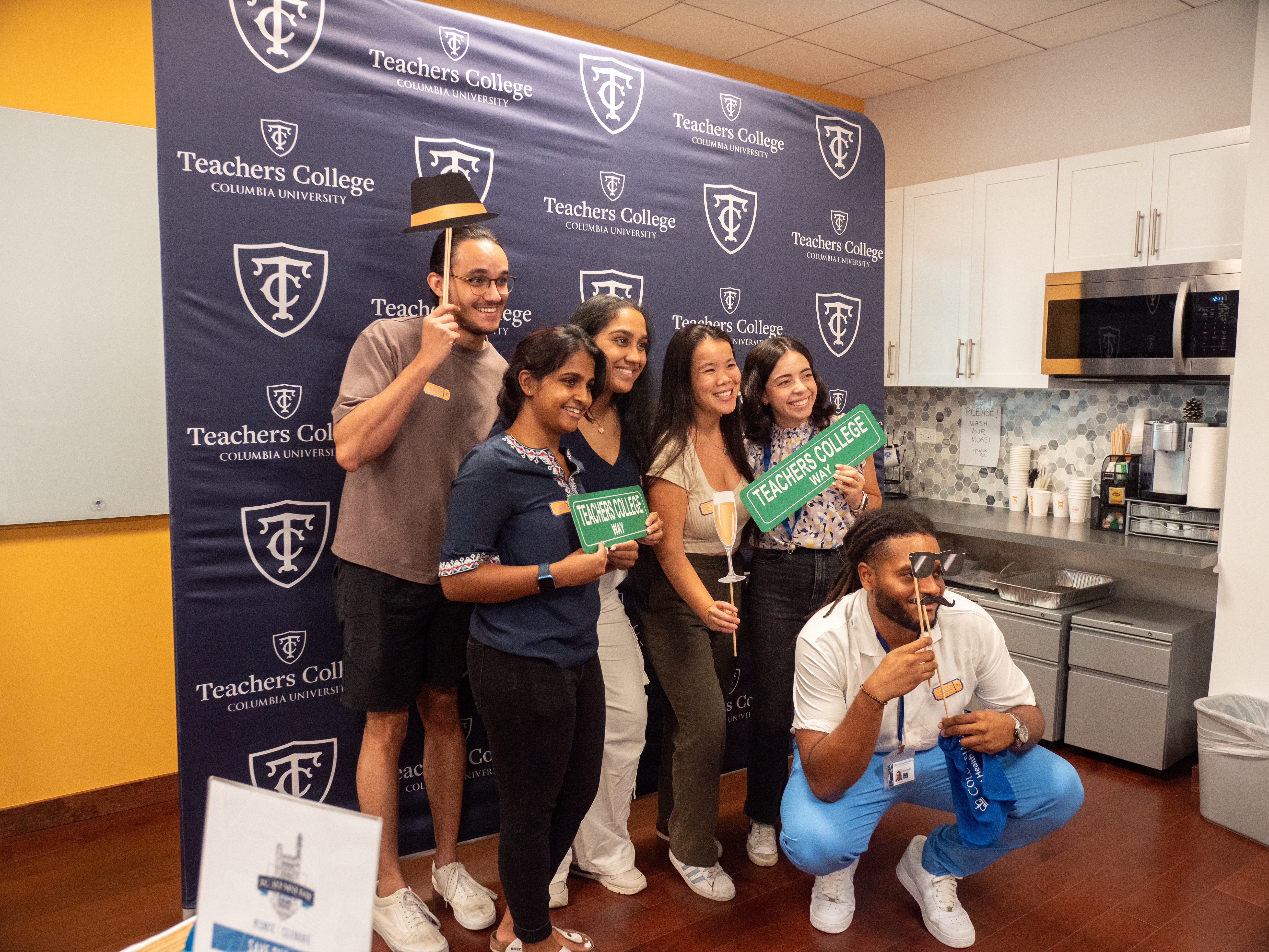 Students posing for photos against a Teachers College photowall