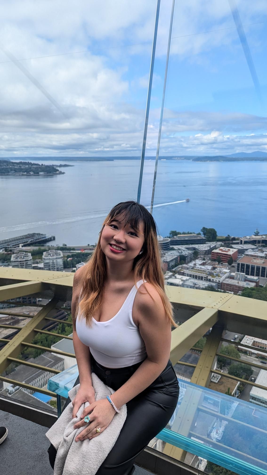 Student sitting near a ledge with a view of water behind her