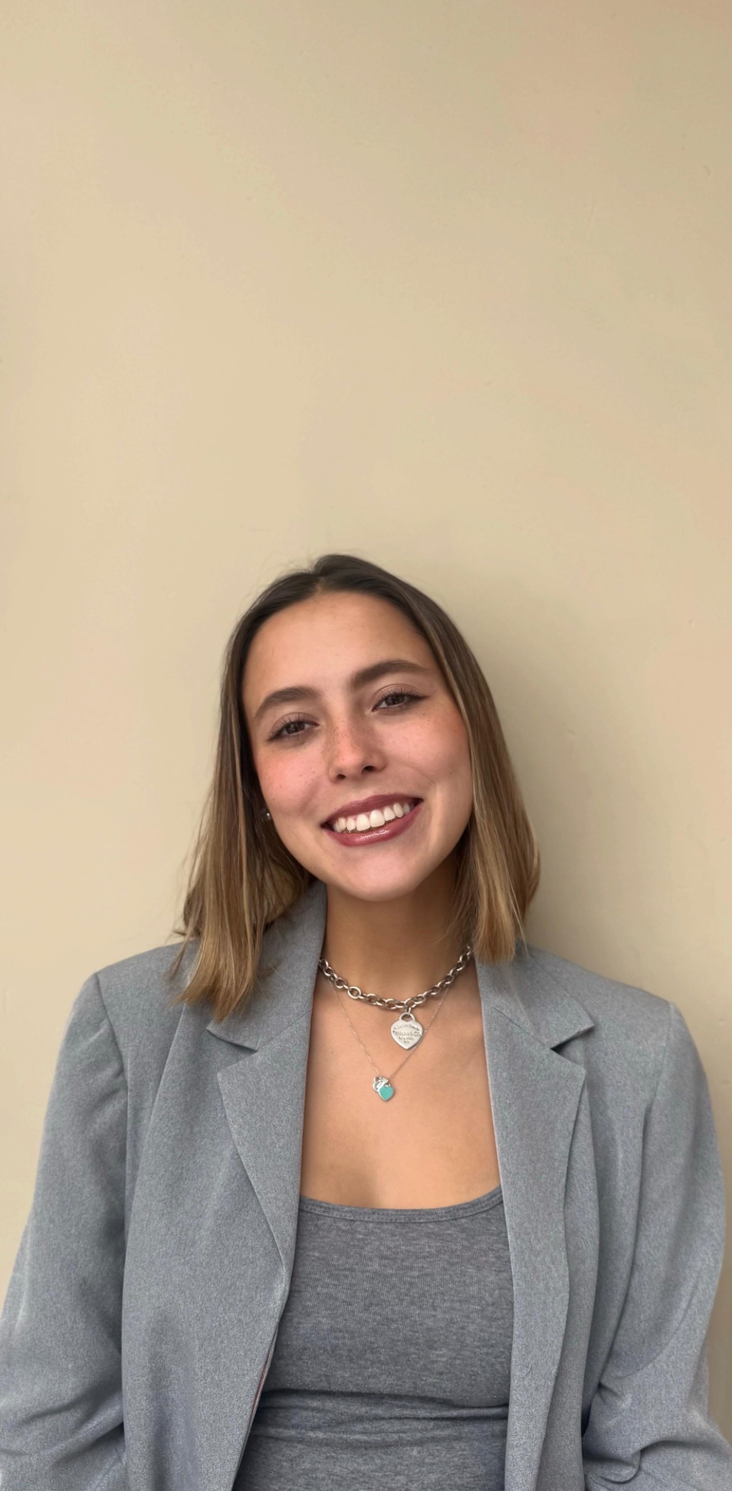 Photo of a student staring right at the camera and smiling in front of a light background