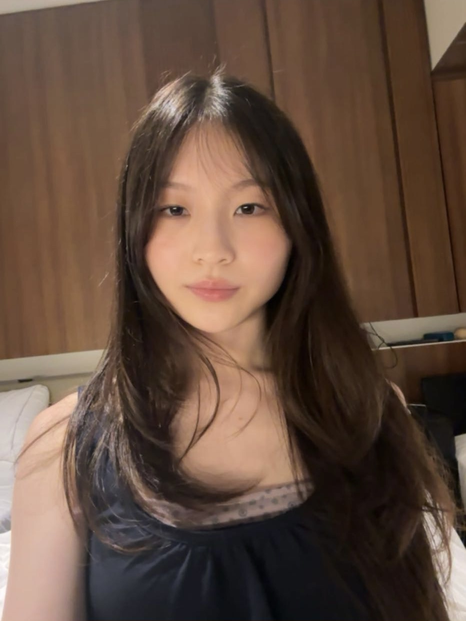Photo of a student smiling at the camera in front of a brown background