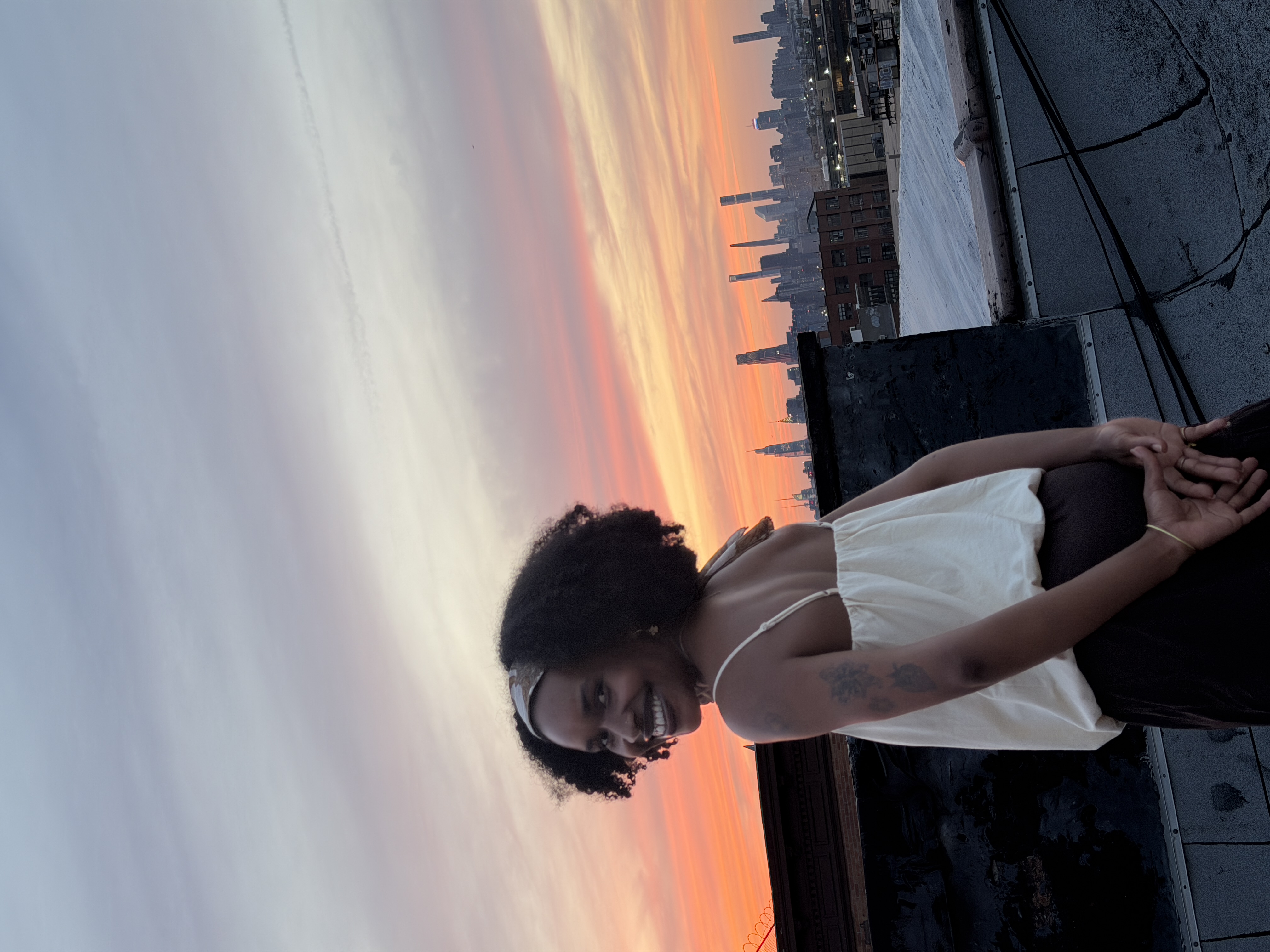 Photo of a student looking over her shoulder at the camera with a sunset in the background