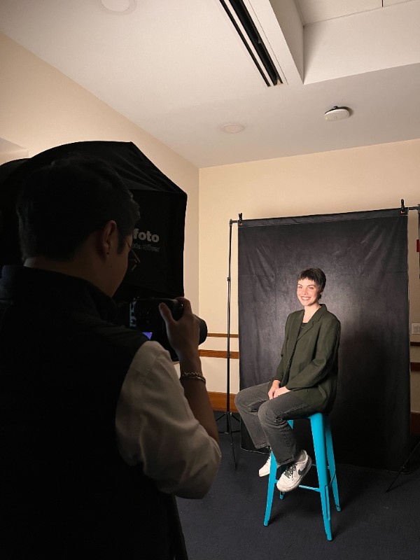 Student poses in front of a black backdrop having their headshot taken