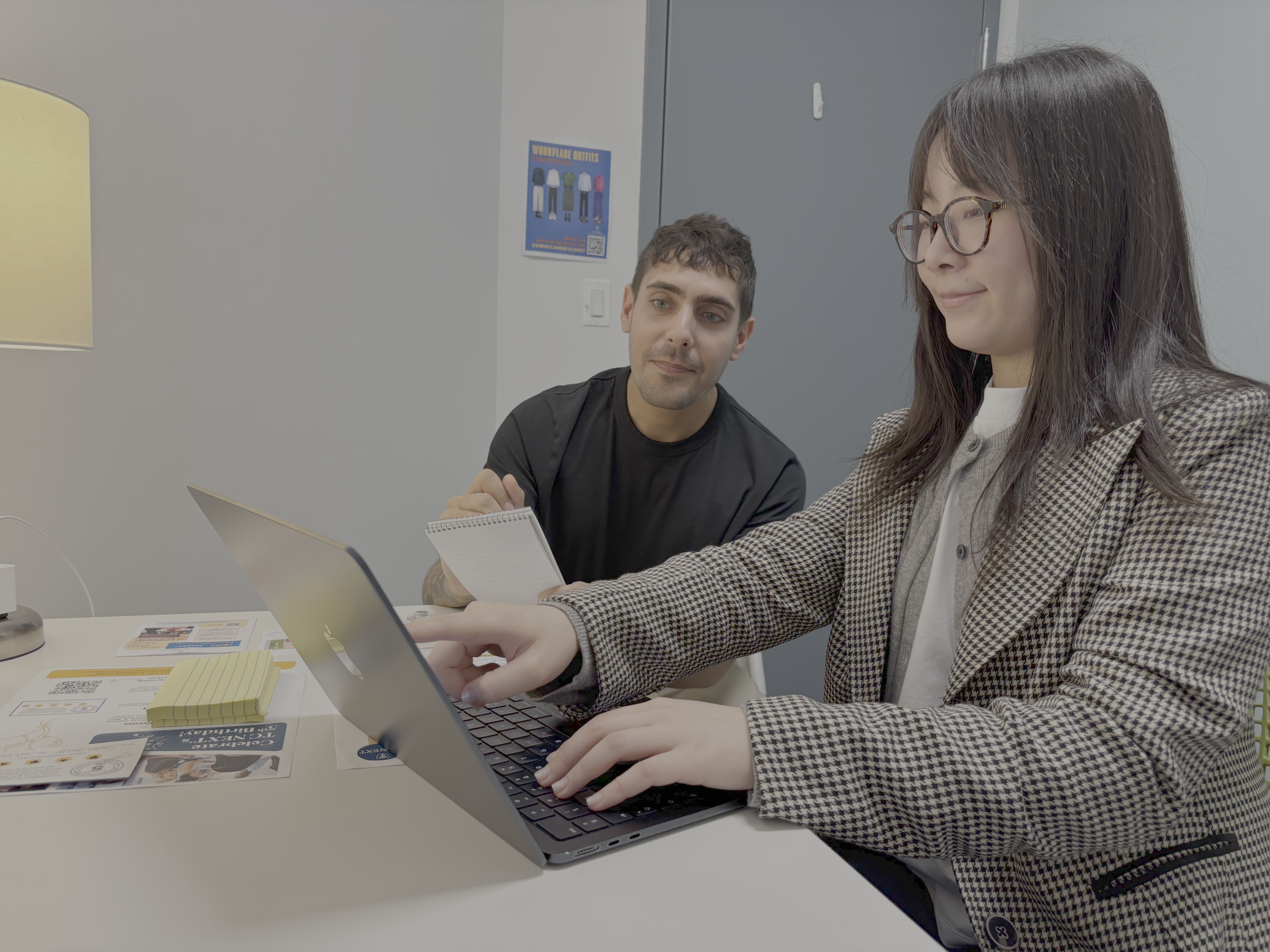 Student sits with coach at a desk, looking at a computer screen