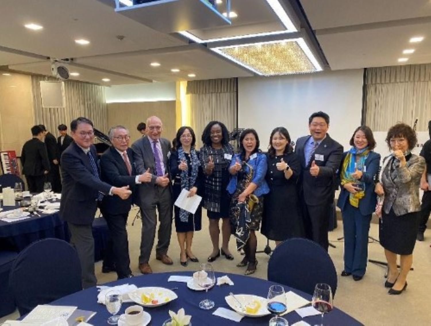 Group of 10 people standing side by side smiling in a meeting room at the President Hotel in Seoul, Korea