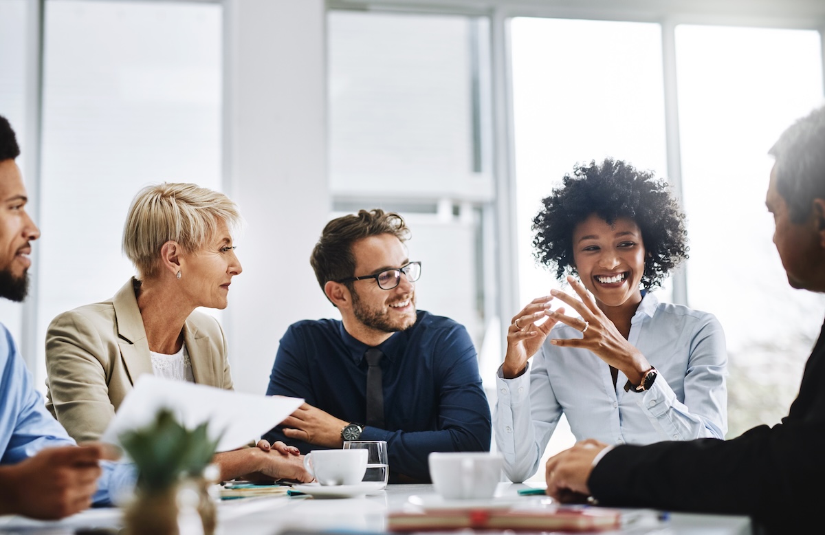 A group of five working professionals in a business meeting setting having a conversation