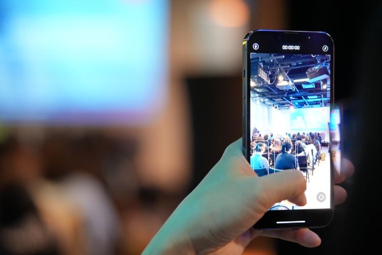 A hand holding an iphone recording the multimodal showcase panel