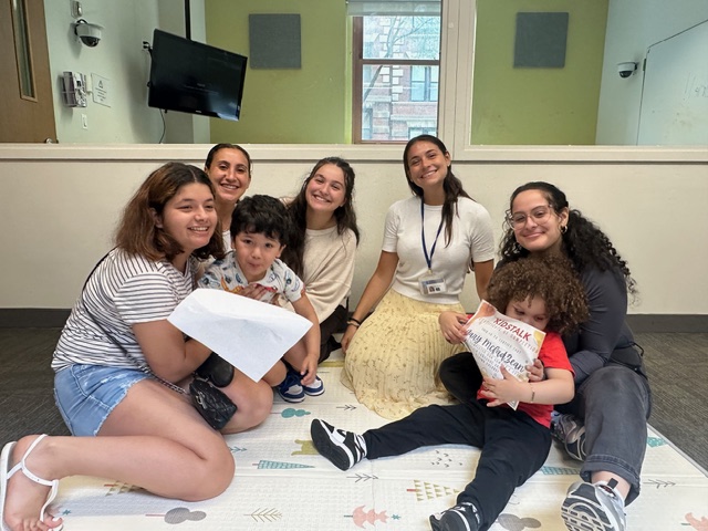Volunteers sit on the floor with two young children during a small group activity and story time.
