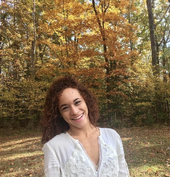 student standing in front of trees