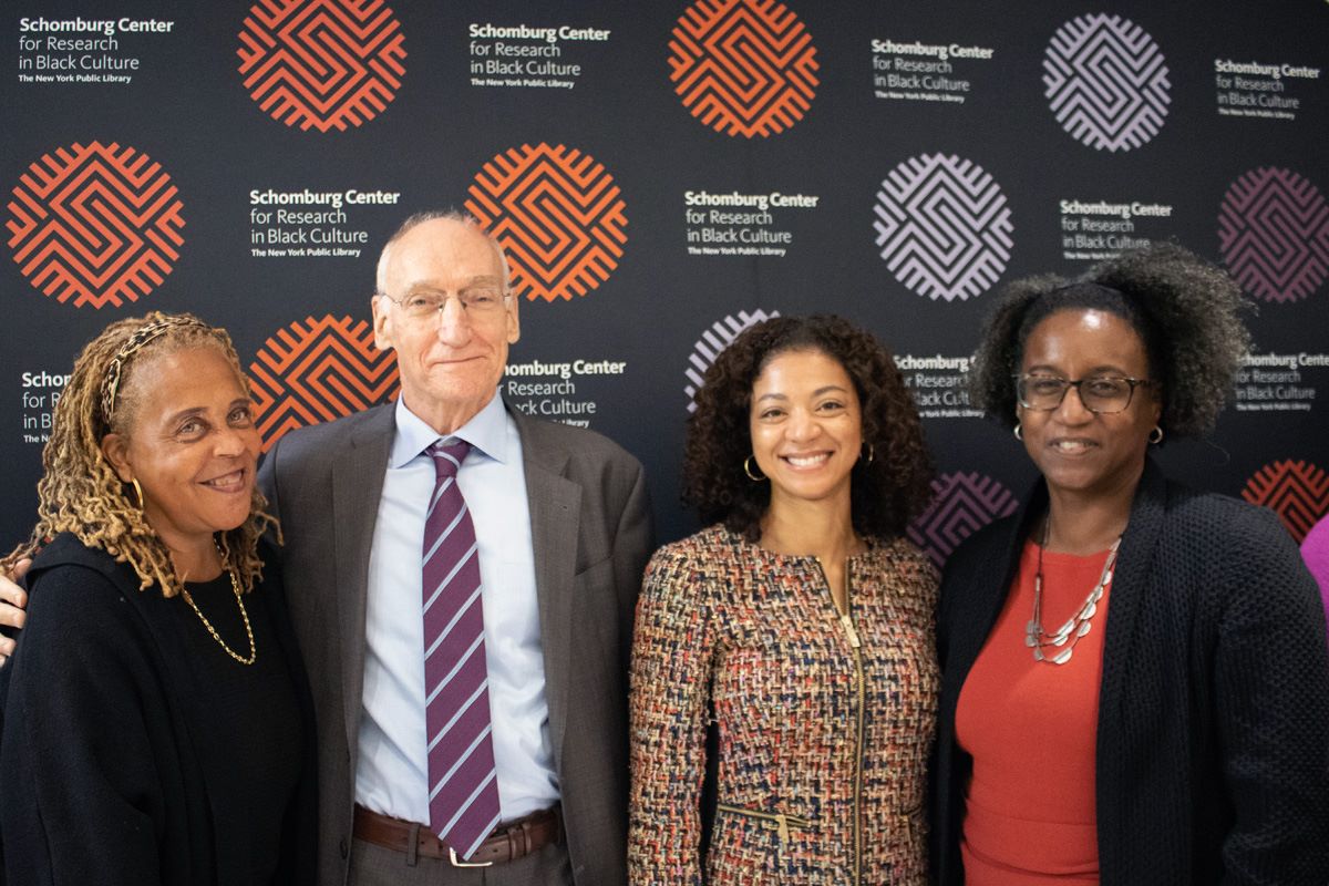 Four people smiling and posing in front of a backdrop
