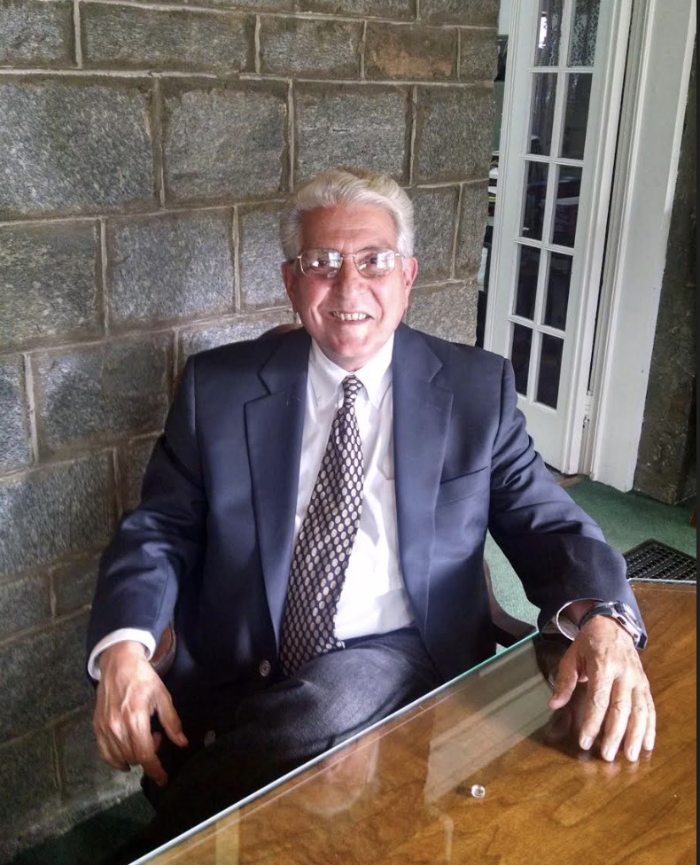 Man wearing a suit smiling while sitting at a table