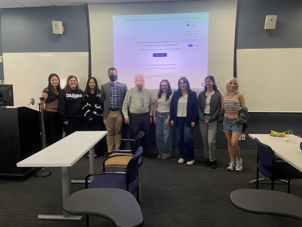 Group standing in a classroom with a presentation on a screen in the background