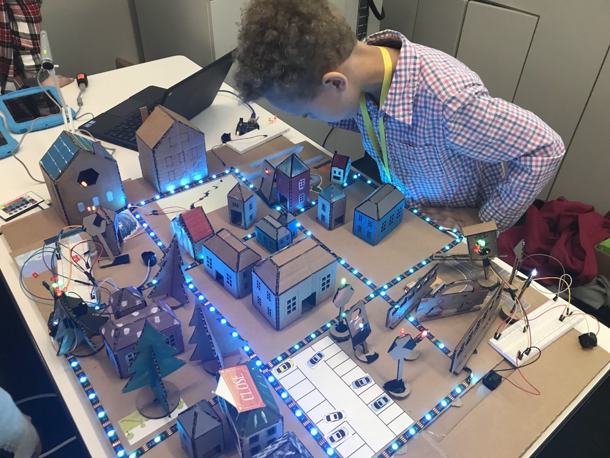 Student looking over a table with a model with buildings and streets made of cardboard and lights