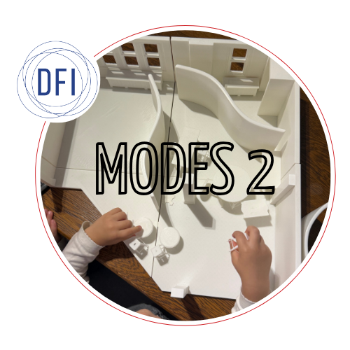 A child’s hands are poised above a white model of an exhibition space with movable walls and furniture.The DFI logo overlaps the top left side.