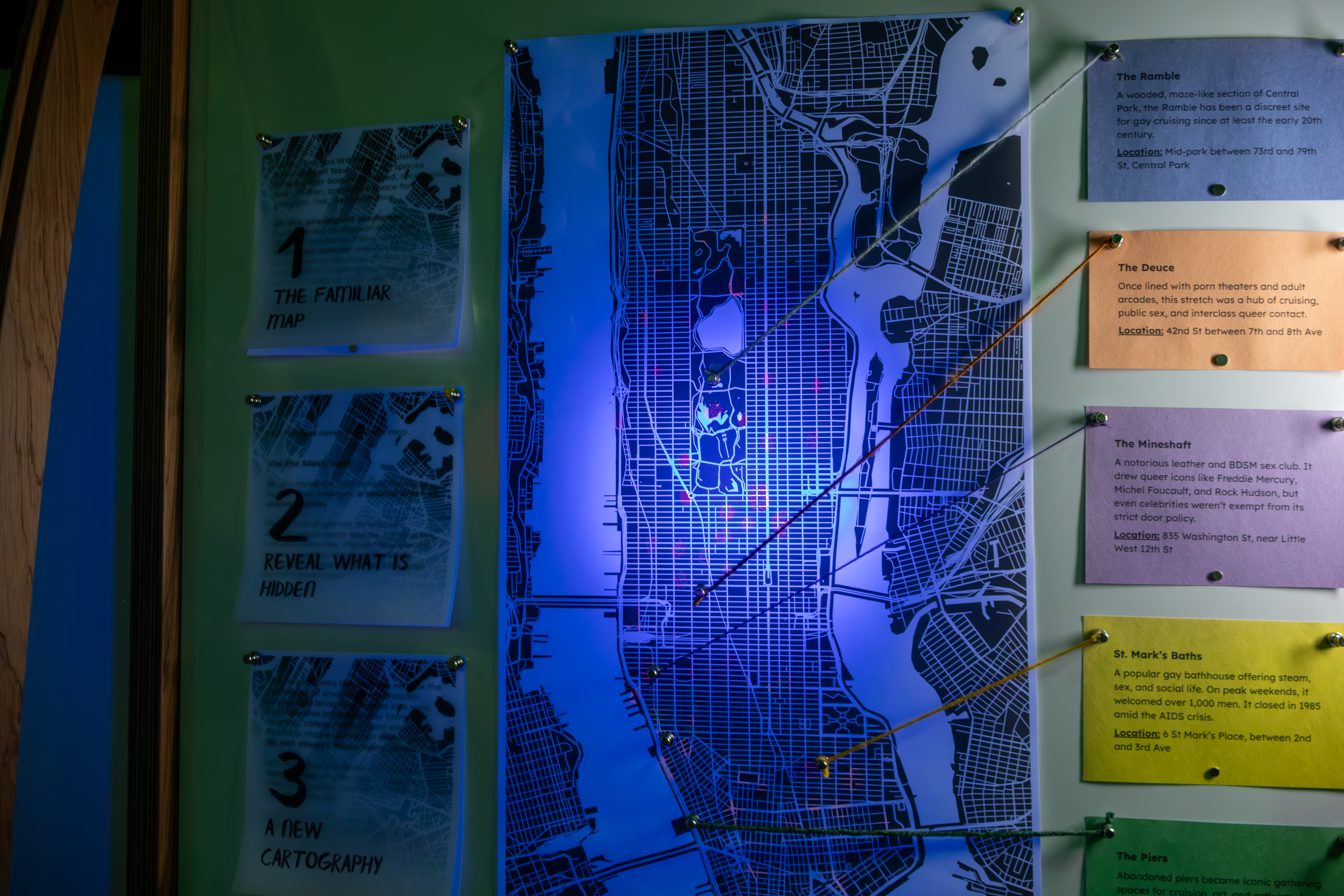 A bulletin board with a large map of New York City with notes and thumbtacks and yarn connecting each note to a point on the New York City map.