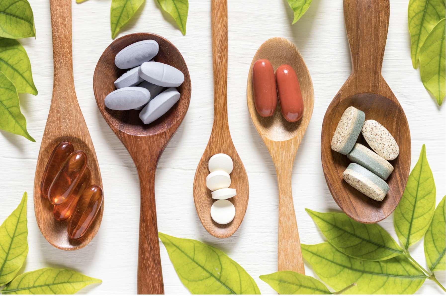 Wooden spoons holding pills of varying colors and shapes