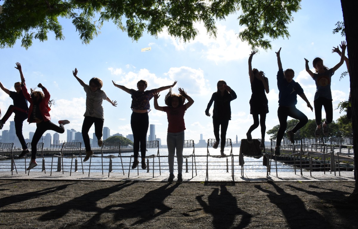 A group of children jumping in a park by the river