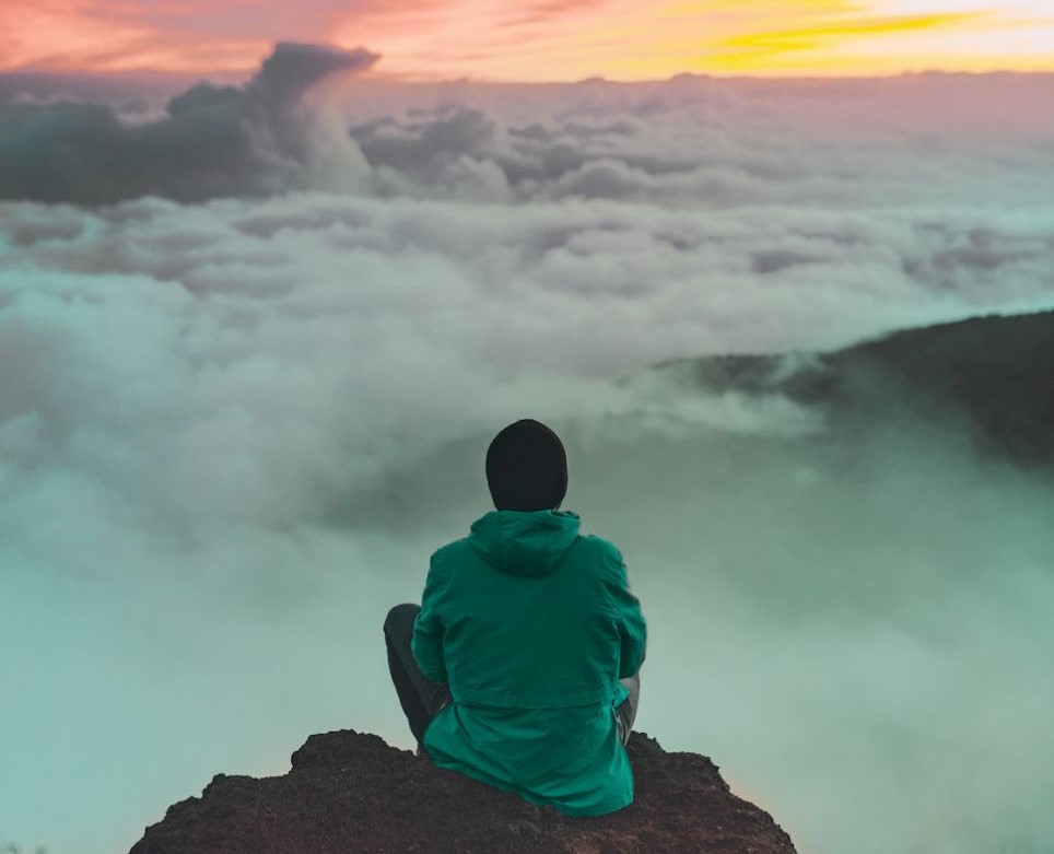 person sitting on rocks looking toward horizon