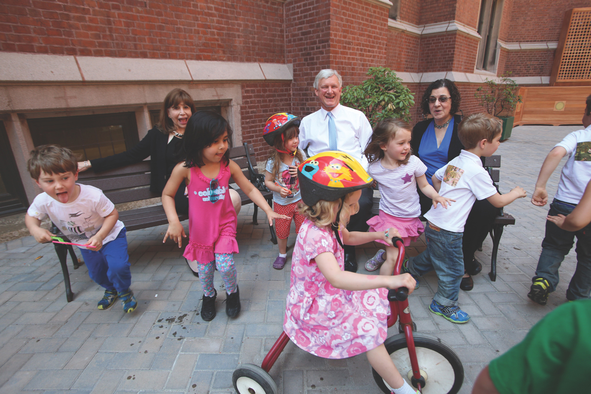 Susan Fuhrman plays with children in the TC courtyard