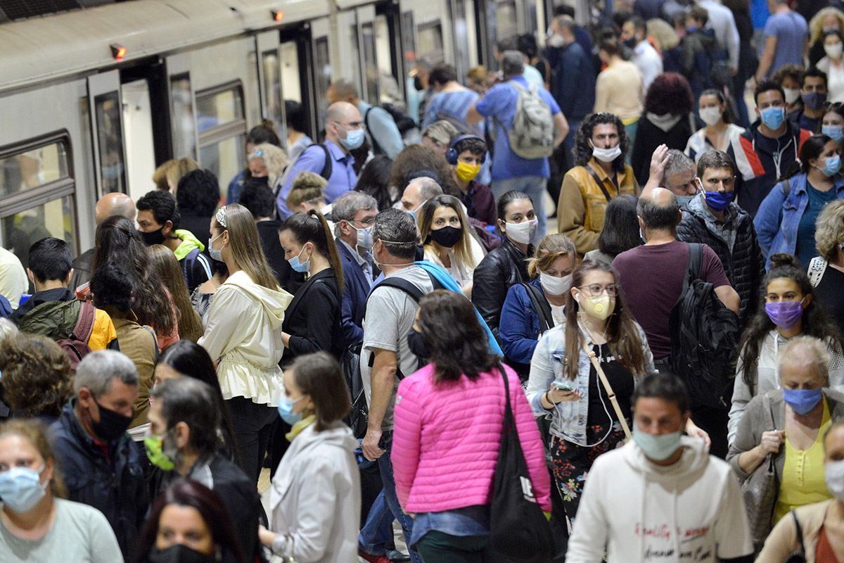 Crowd of people getting off train in masks