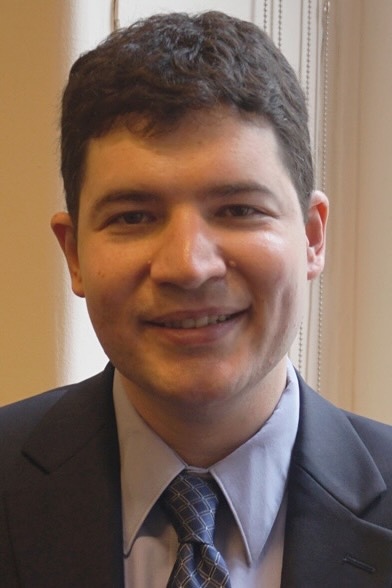 benjamin lovett smiling at the camera. He has fair skin, short hair and is wearing ablue suit.