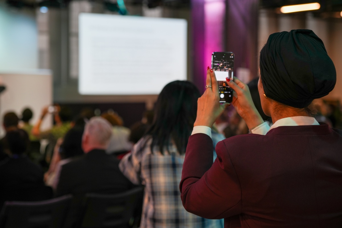 Guest takes a smartphone picture of the presentation at AIRiAL 2024.