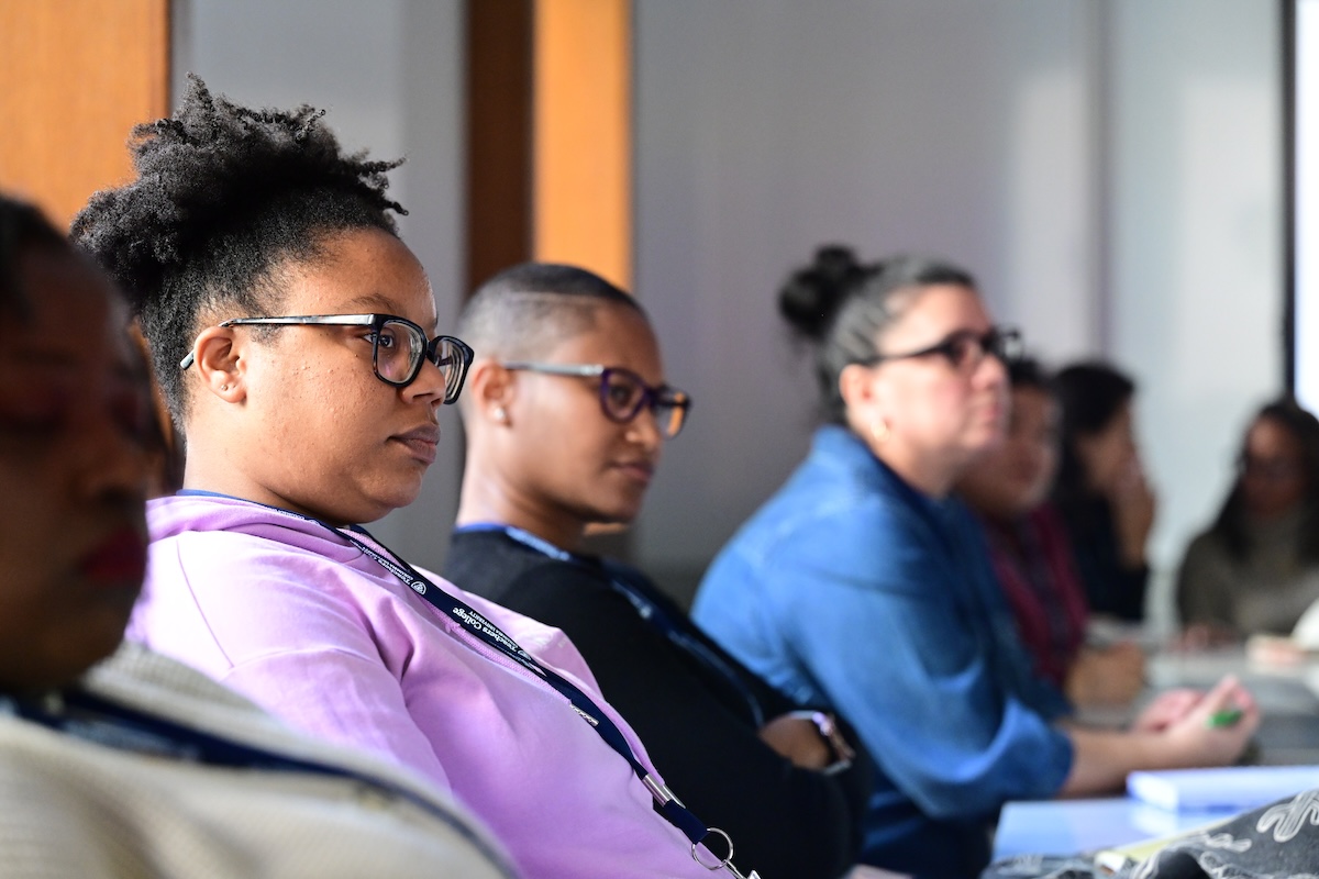 People sitting in a row next to each other looking at a speaker.