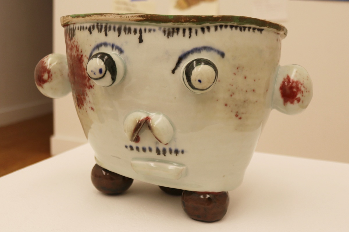 A porcelain basin painted with an underglaze. Pot resembles a face, with circular eyes, ears and mouth.