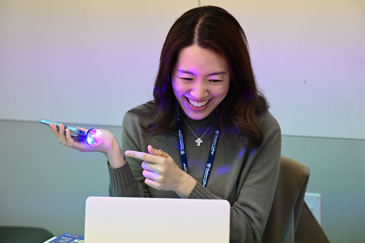 Jennifer Ku using a flashlight attached to her phone and smiling