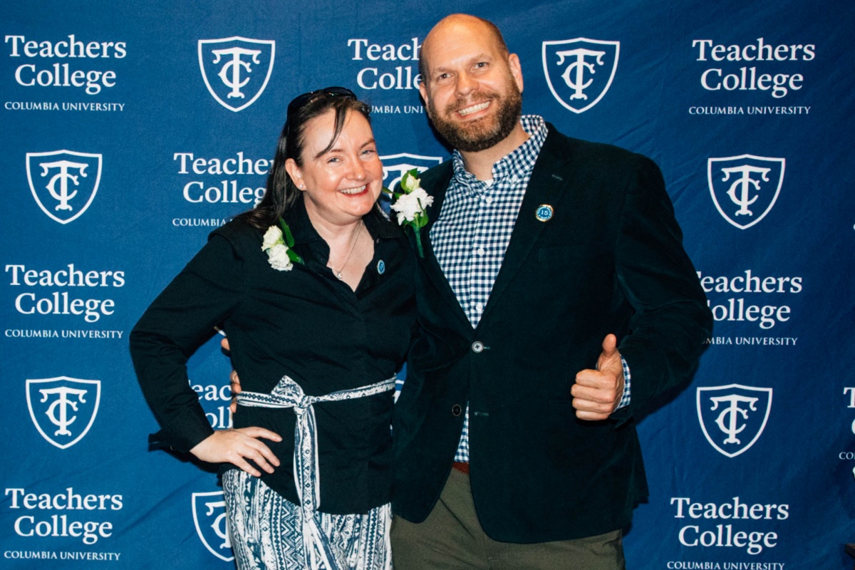 Photo of two staff members smiling, one holding a thumbs up