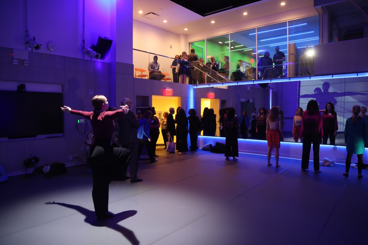 Dancer performs in a vast, blue-lit studio in front of an audience