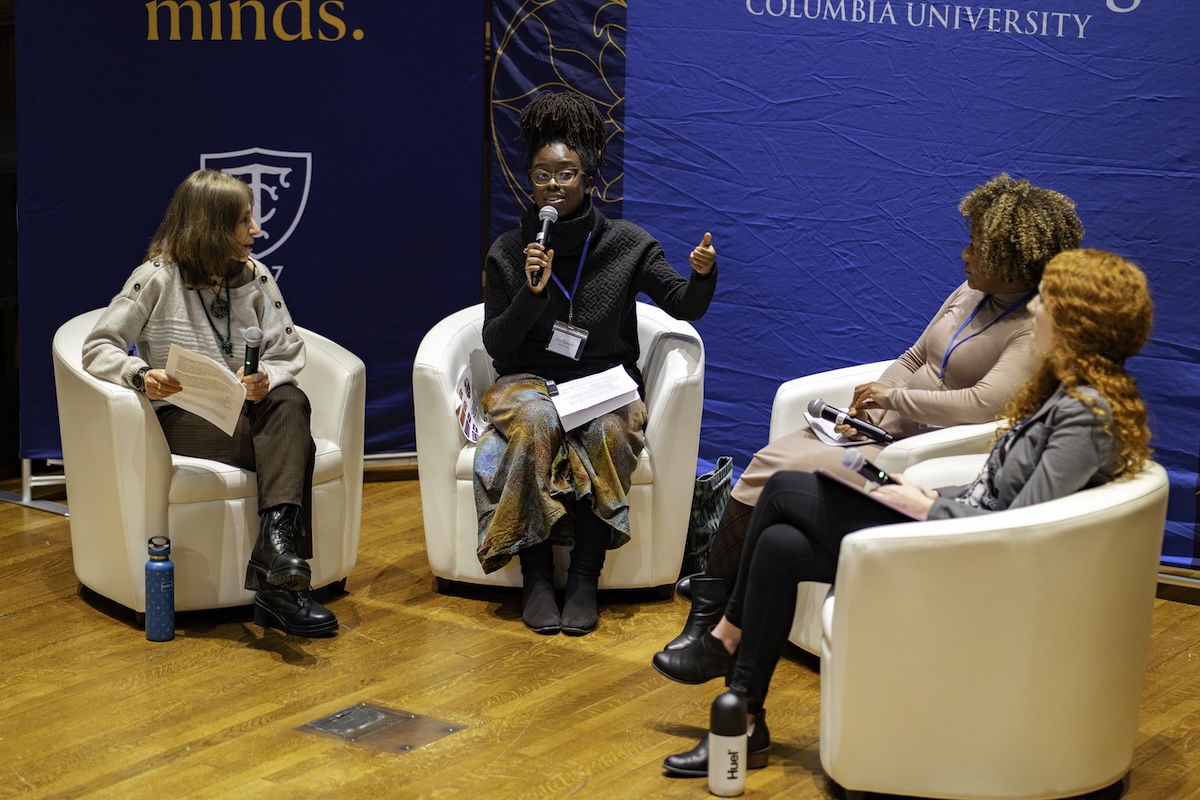 Four women sitting in white chairs and holding microphones