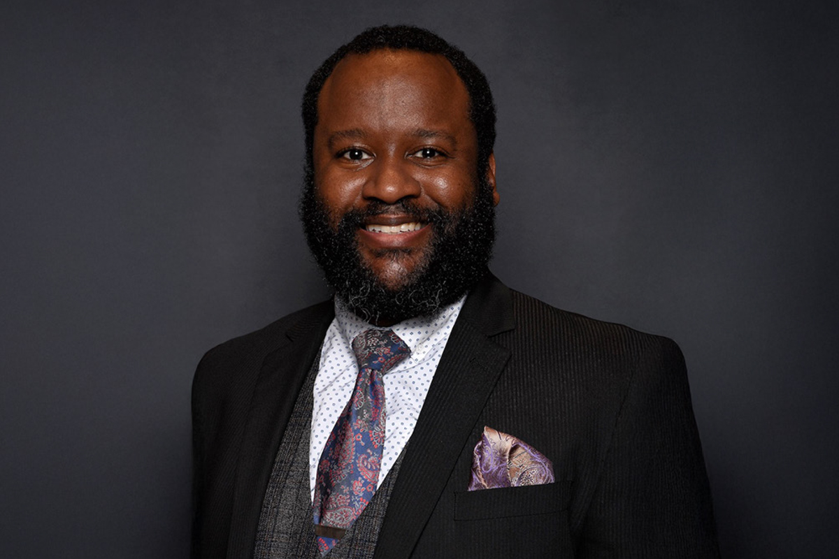 Drew Coles in a black suit with a purple tie and handkerchief