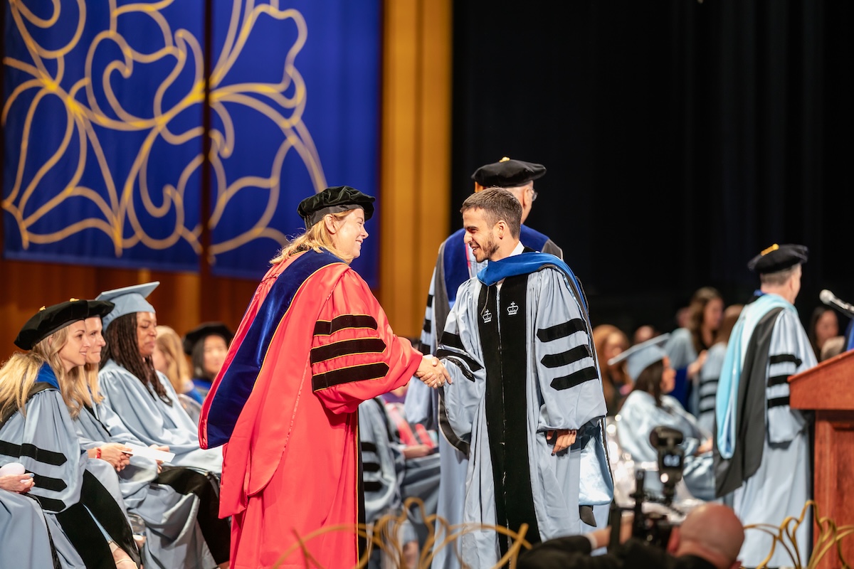 Provost KerryAnn O'Meara shakes hands with graduate.