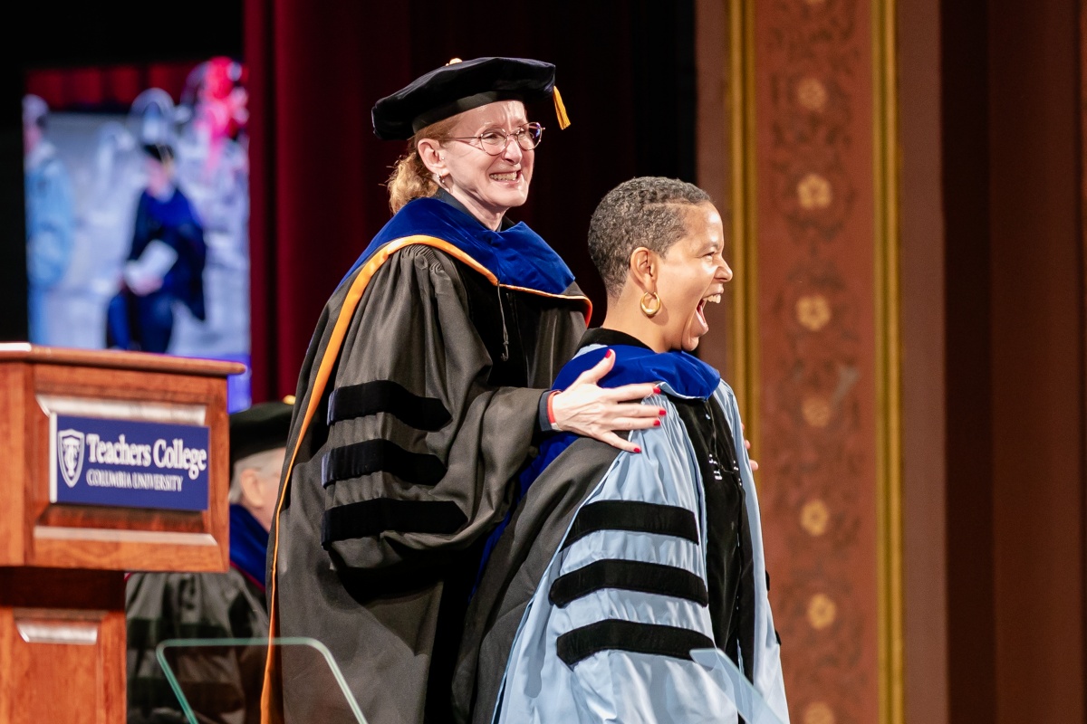 A doctoral graduate receives her hood.