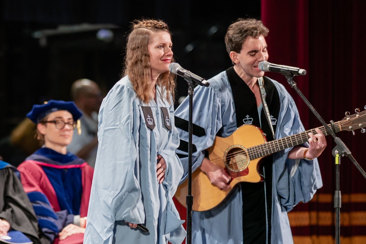 Woman sings next to man with guitar
