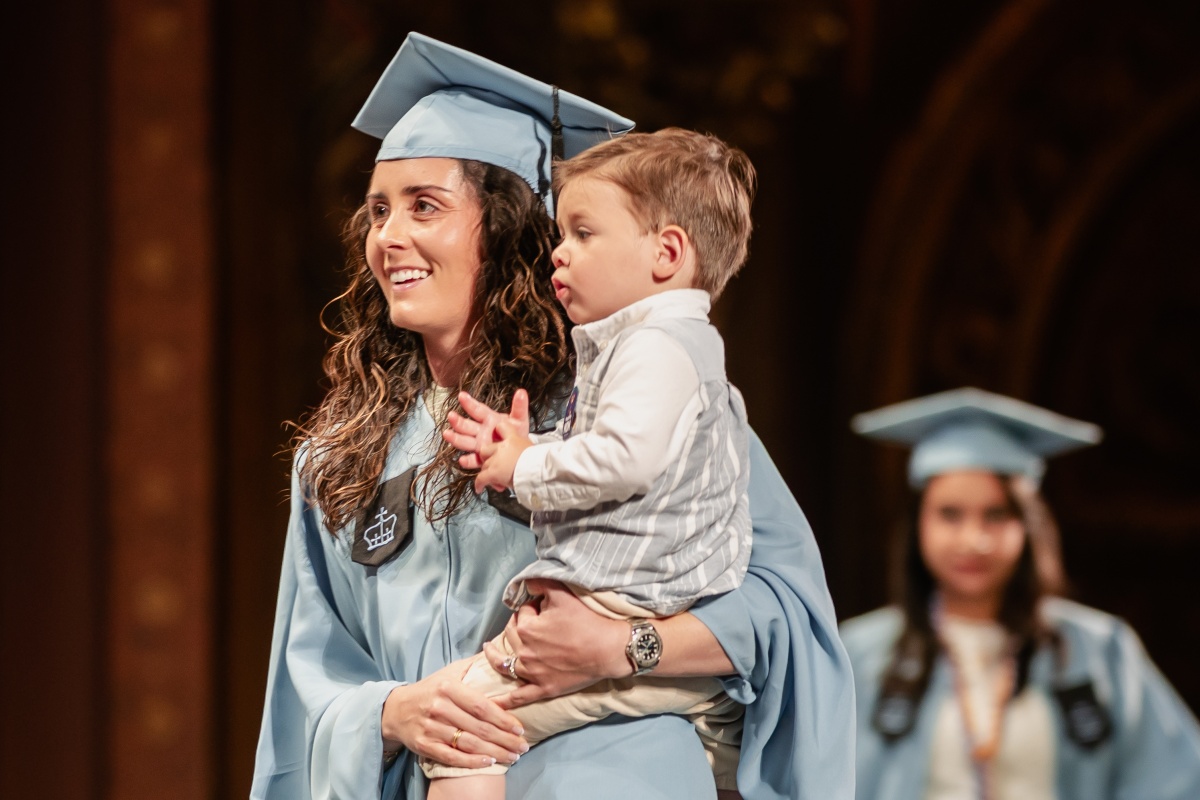 A graduating student from the Class of 2025 receives her diploma with her son.