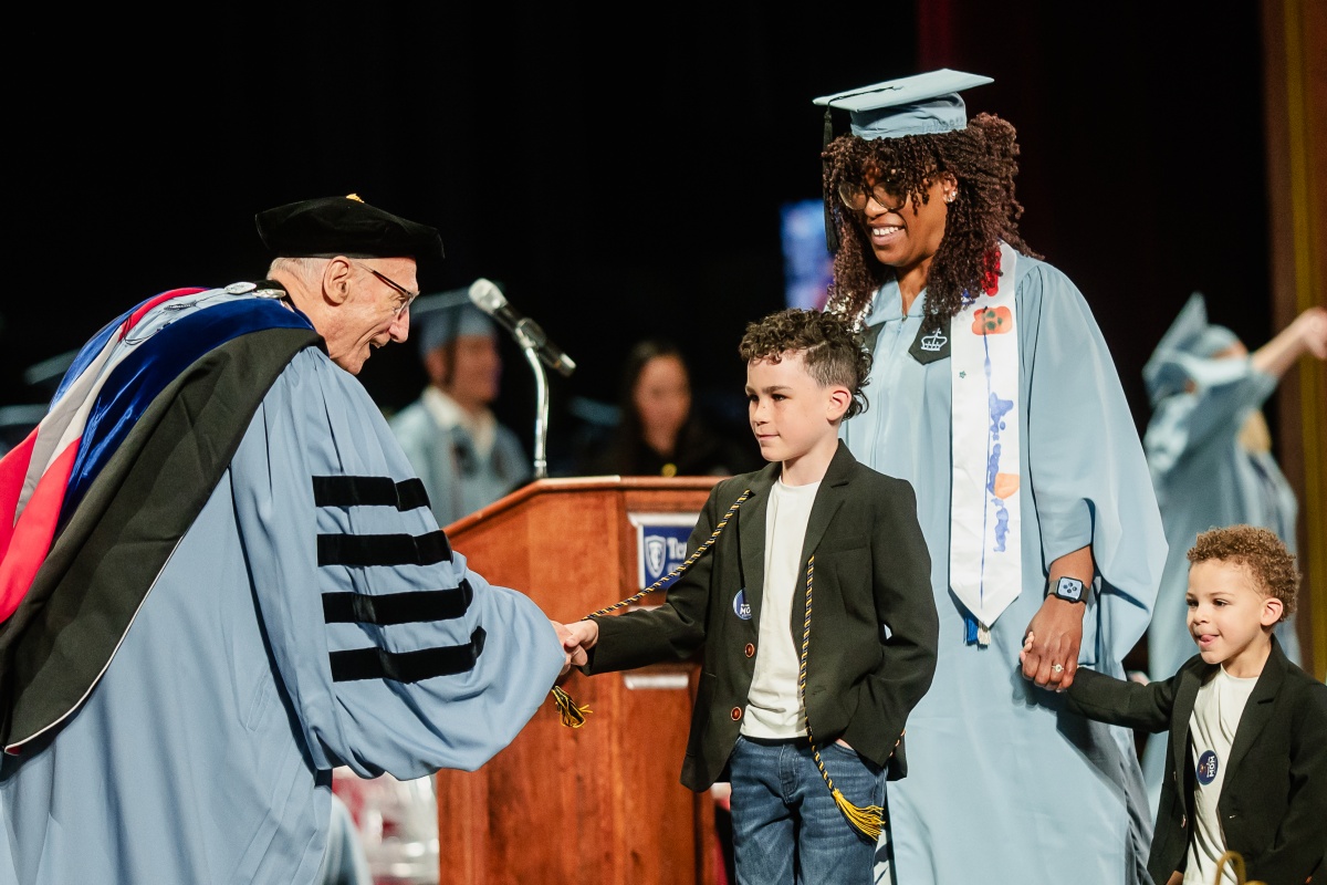 President Bailey shakes hands with the child of a 2025 graduate.