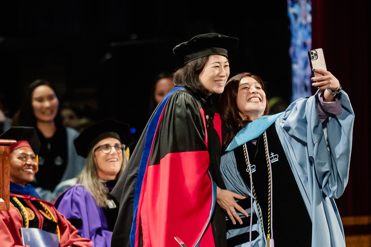 Doctoral grad takes selfie with doctoral adivser on stage