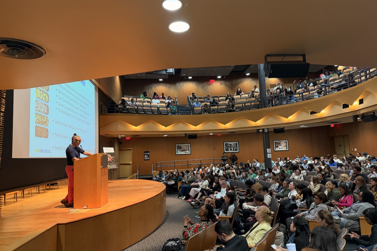packed audtorium with a speaker at a podium