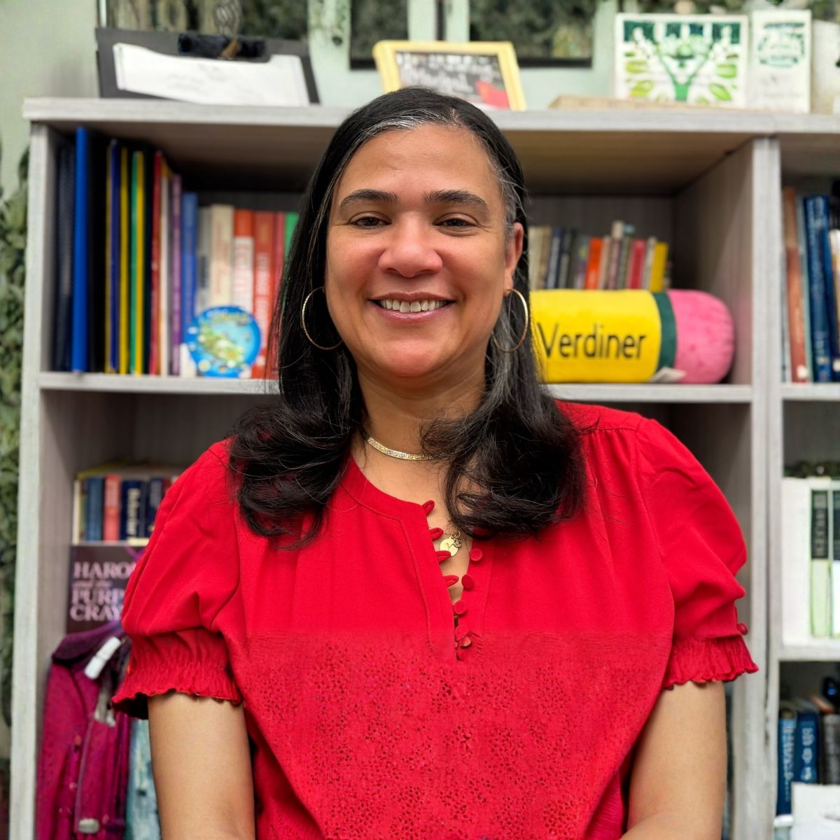 Michelle Verdiner smilinng in a classroom, wearing a red shirt