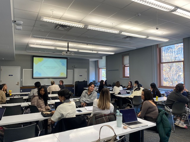 A picture of students engaging in discussion at a GWC workshop: Writing the Literature Review. Students are sitting at tables and actively speaking with one another.